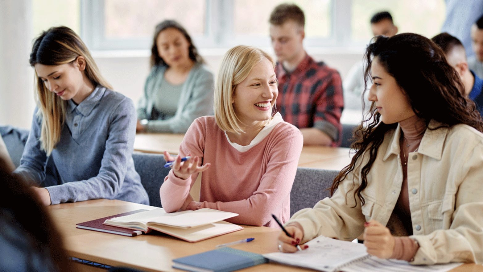 Lernende arbeiten in Kleingruppen an Tischen in einem Klassenraum