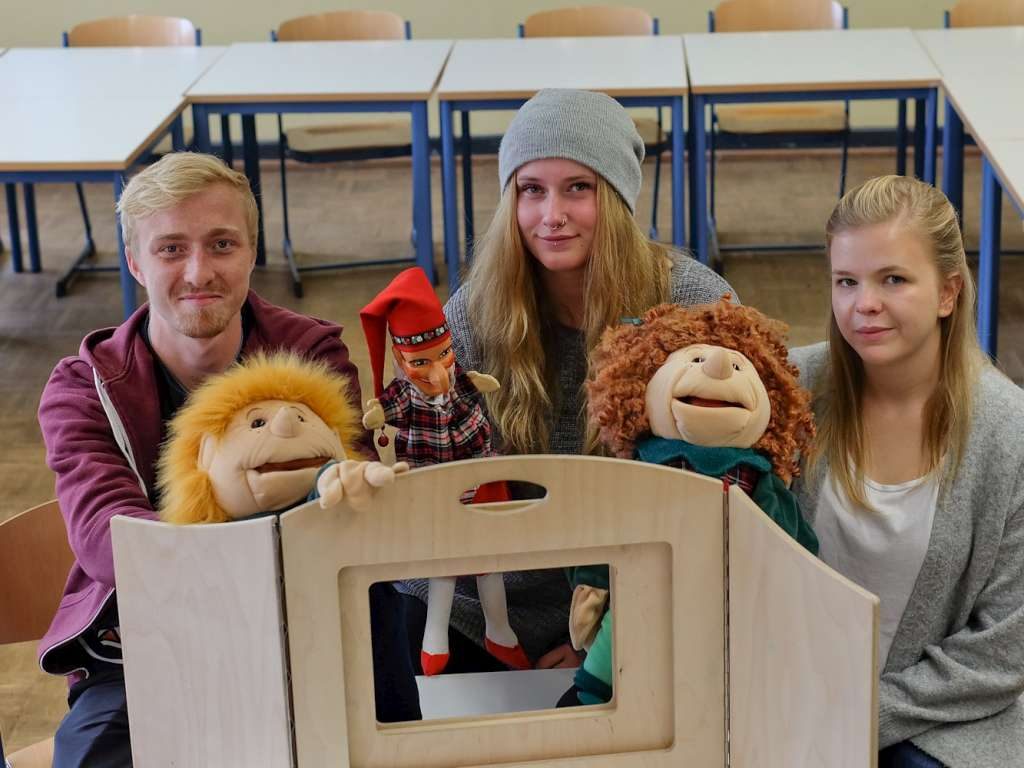 Lernende stehen mit Handpuppen hinter einer Puppenbühne