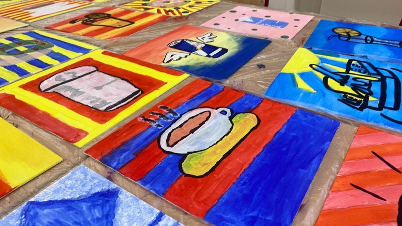 Bunt bemalte Bilder liegen nebeneinander auf einem Tisch