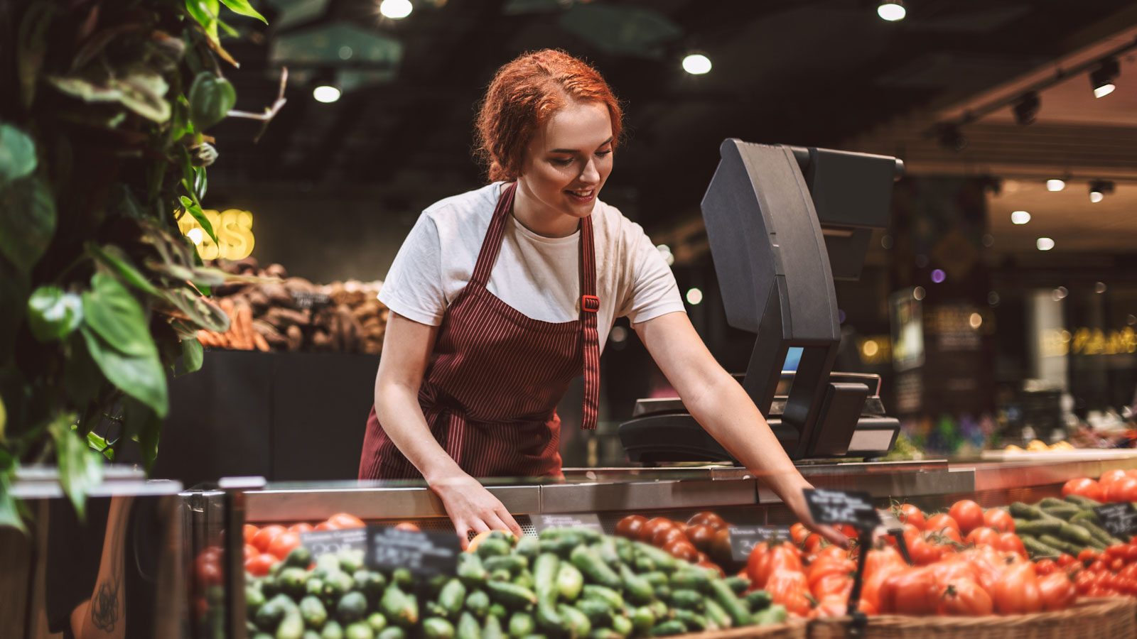 Eine Verkäuferin räumt die Obst- und Gemüseauslage ein