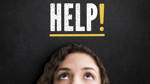 Tafelbild mit der Aufschrift HELP, darunter blickt eine junge Frau nach oben