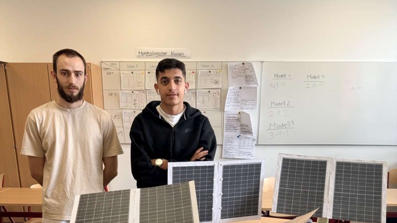Zwei Lernende stehen im Klassenraum hinter aufgestellten Solarmodulen