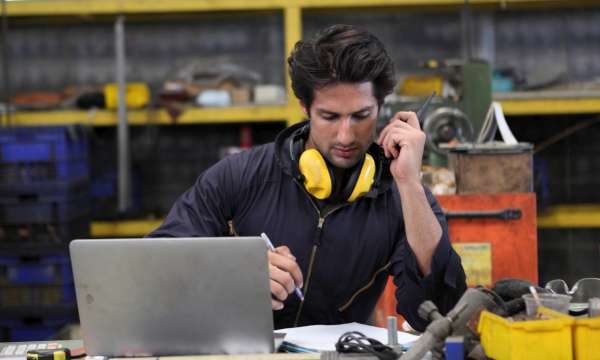 Eine Fachkraft arbeitet in der Werkstatt an einem Laptop