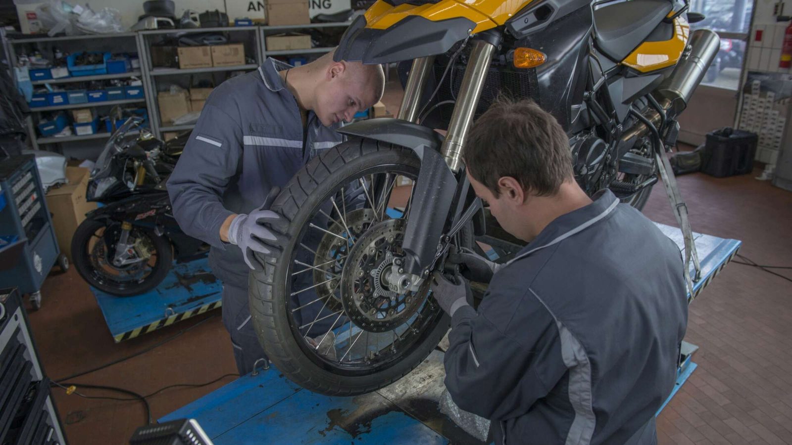 Zwei Lernende arbeiten in der Werkstatt am Vorderrad eines Motorrads
