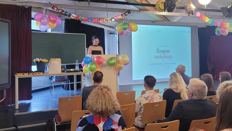 Zeugnisverleihung in der Aula, eine Lernende spricht am Rednerpult vor dem Publikum